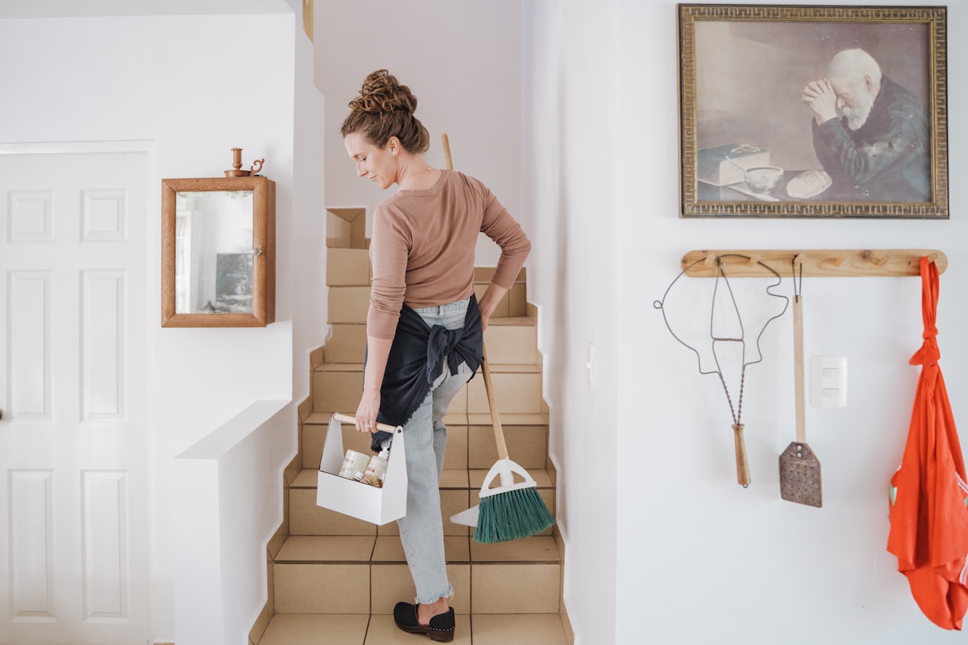Cleaning professional carrying supplies up a stairway in a home